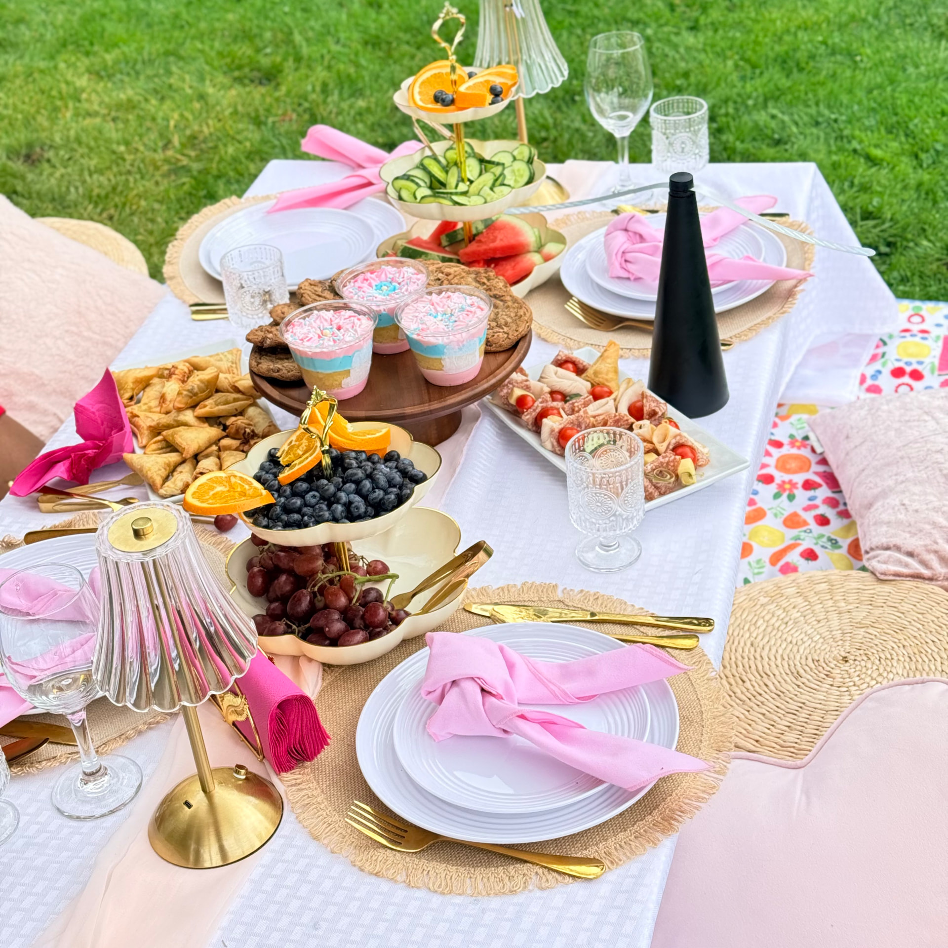 Luxury picnic tablescape with pink linens, gold cutlery and fresh fruit