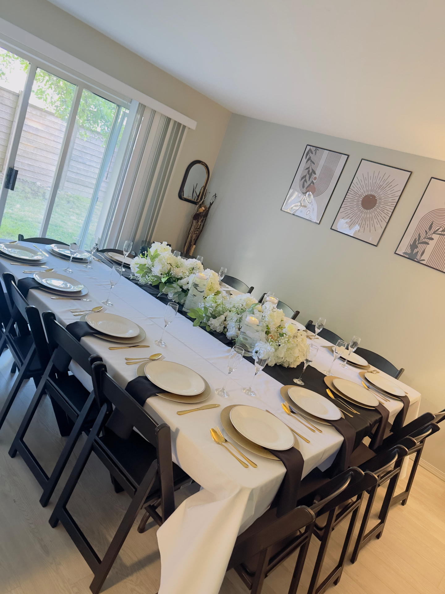 Elegant dining tablescape with white florals, black napkins and gold cutlery